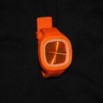 A watch that is orange and has an arrow on it.