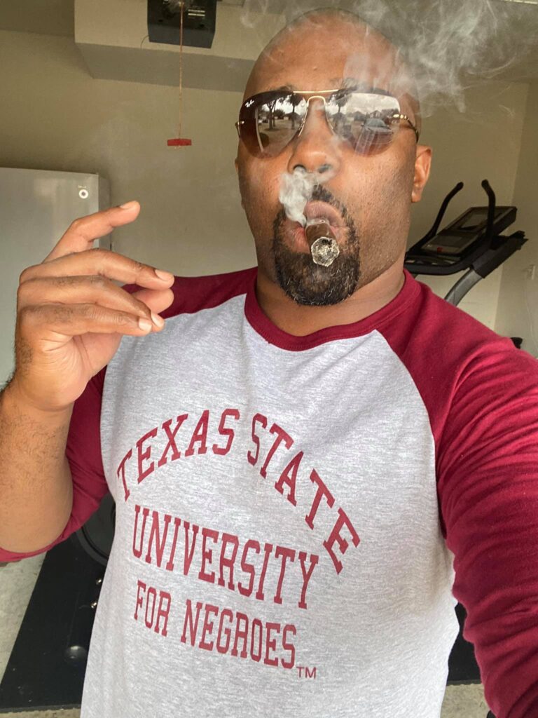 A man with sunglasses and a beard smoking.